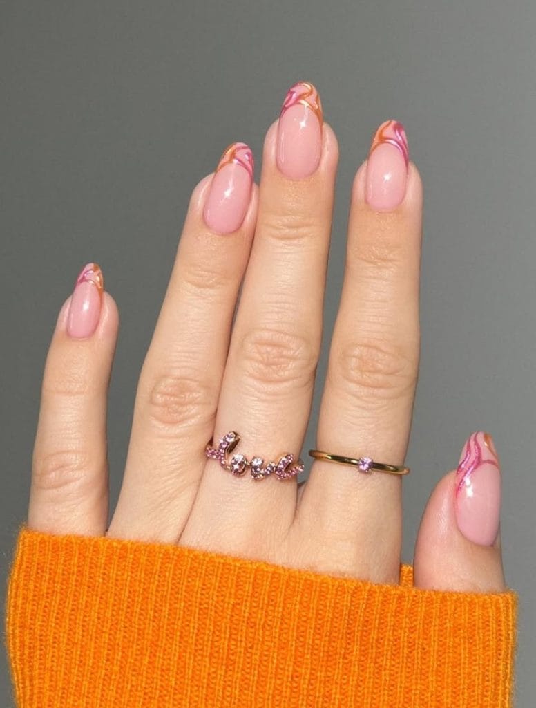 oval vacation nails with pink base and coral orange swirl French tips
