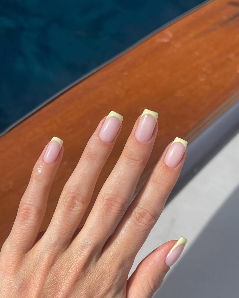 square vacation nails with nude base and yellow French tips