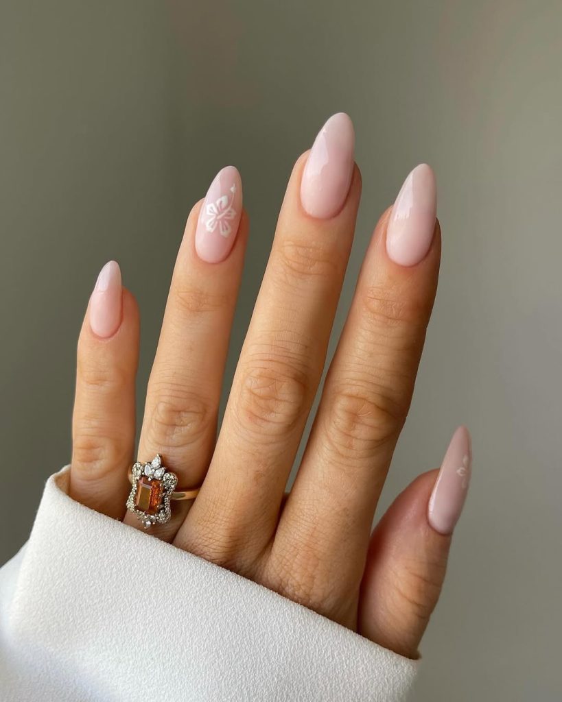 Almond nails in nude color with white hibiscus flower accent design creating classy summer manicure