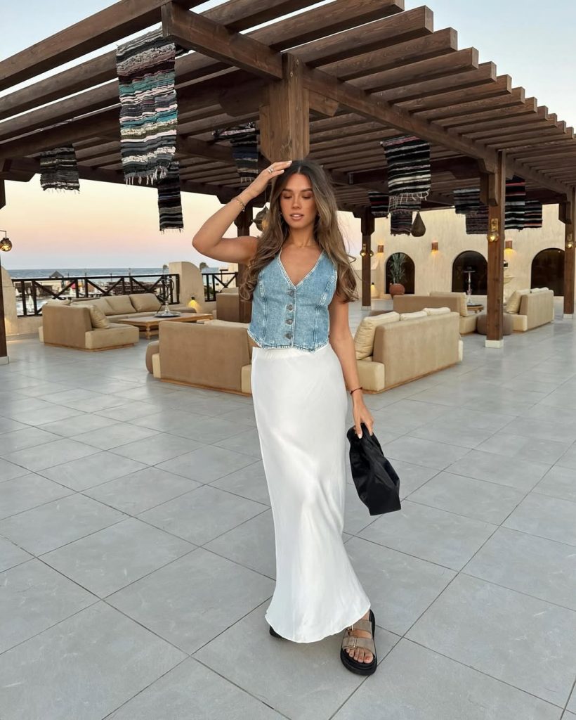 Casual summer outfit with light blue denim button-front vest top, white silk maxi skirt, black pouch bag and platform leather sandals