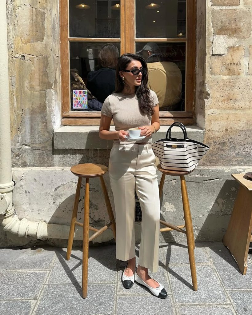 Minimalist summer work outfit with beige fitted t-shirt, cream straight-leg trousers, black-toe ballet flats and striped structured tote bag