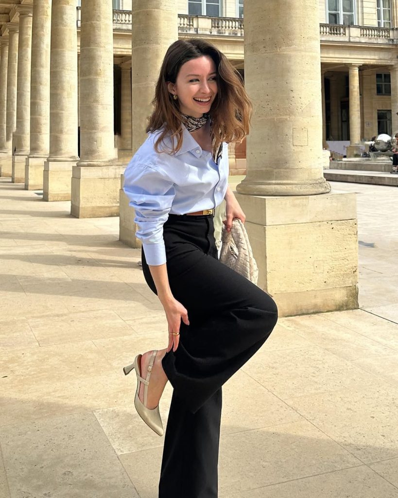 Summer outfit with light blue button-down shirt, black wide-leg trousers, printed neck scarf, gold belt and quilted cream handbag