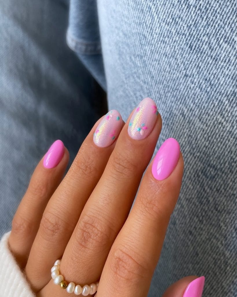Short oval vacation nails with hot pink and iridescent pink polish with small floral accents
