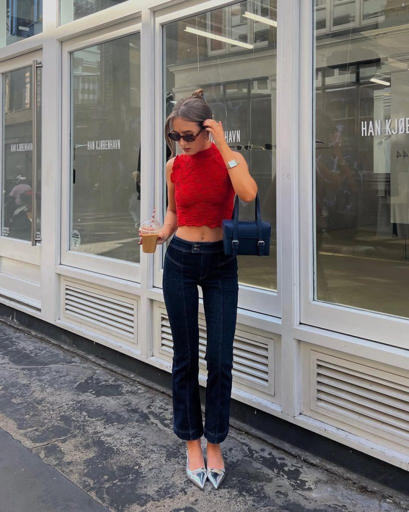 summer date night outfit with red textured sleeveless crop top, high-waisted dark denim jeans, metallic silver pointed heels and navy structured handbag