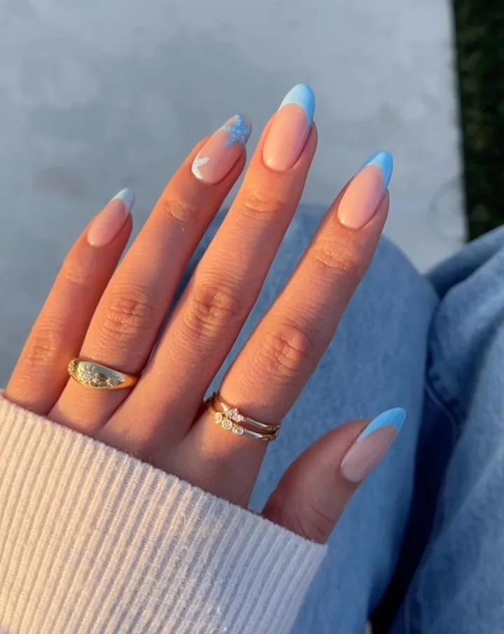 Almond simple summer nails with baby blue French tips and white floral accent nail on nude base