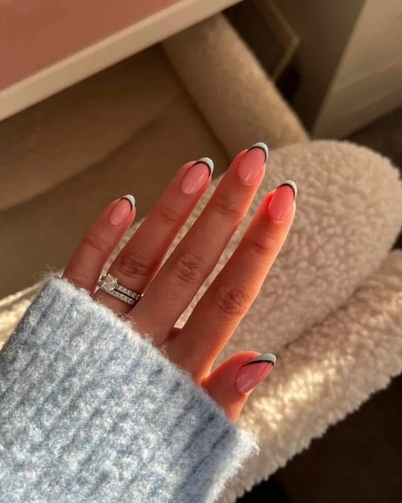 Simple summer almond nails with sheer pink base and light blue French tips with thin dark brown outline