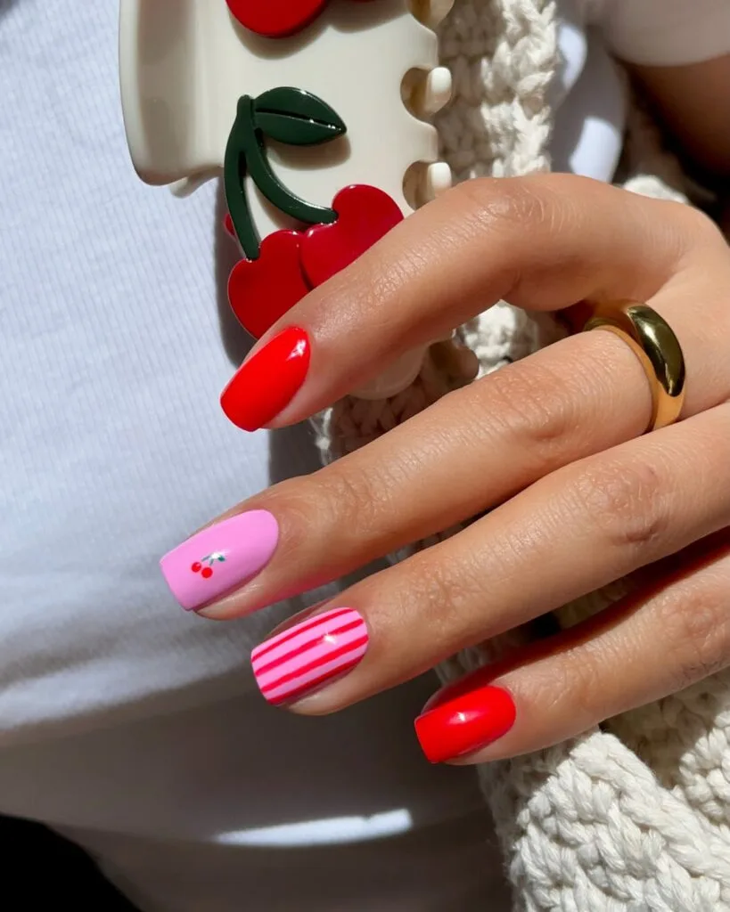 short summer nails, red and pink mix with tiny cherry accent and striped nail, square shape
