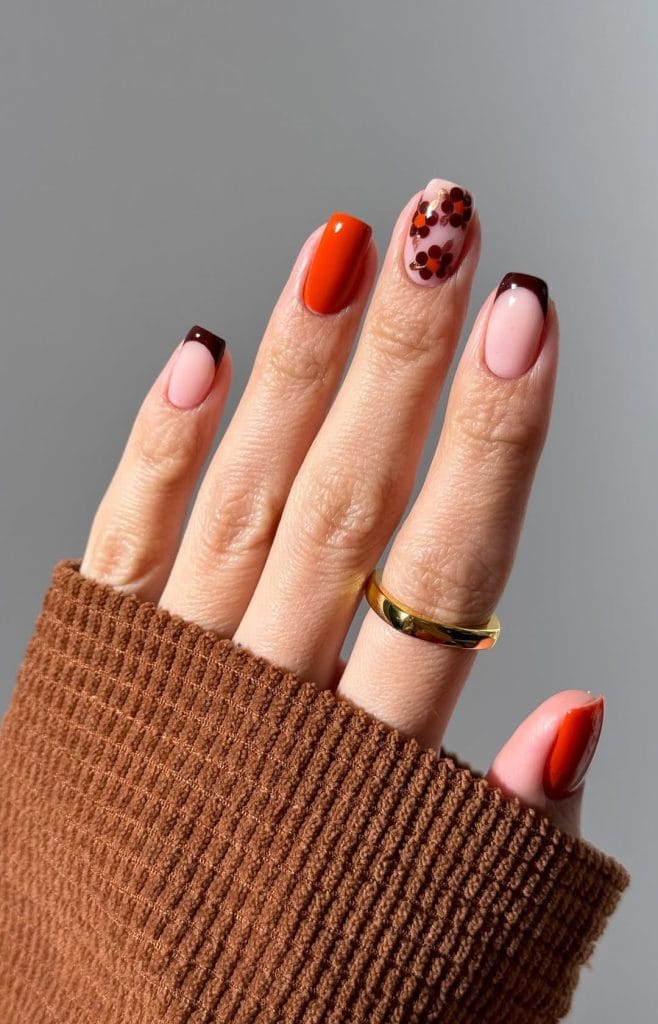 Short fall nails with burnt orange, pink base with burgundy floral design, and chocolate brown French tips
