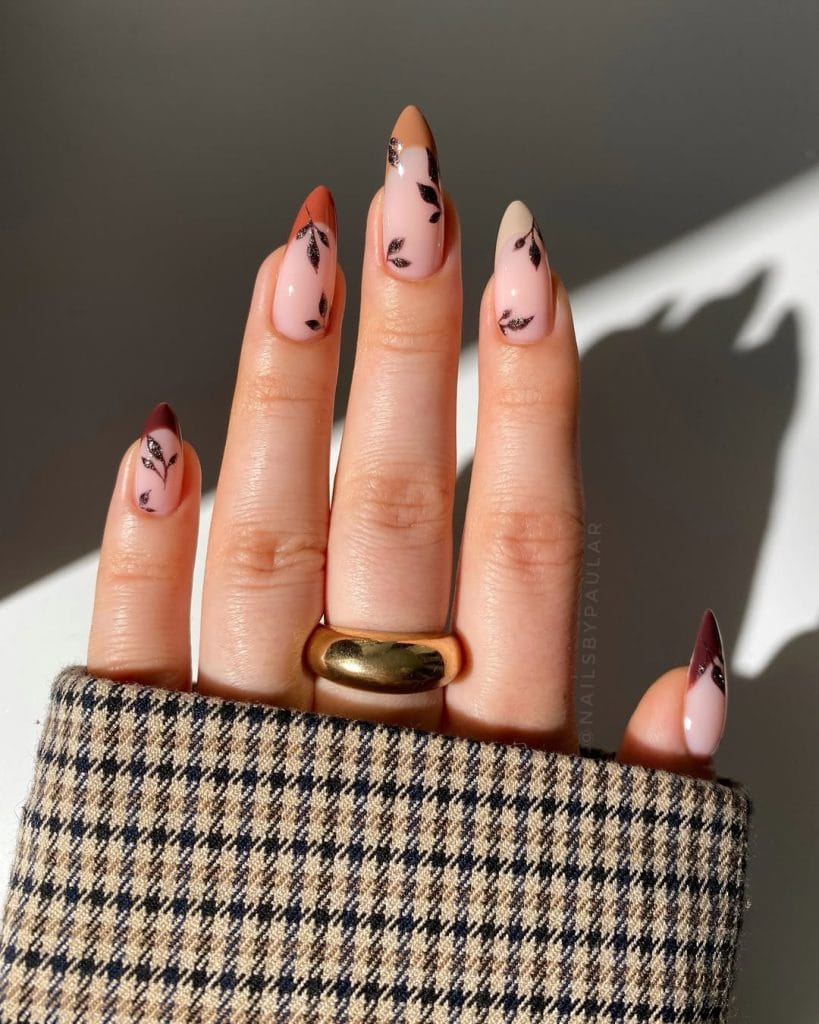 Long almond fall nails with gradient French tips from peach to orange and black leaf nail art on each nail
