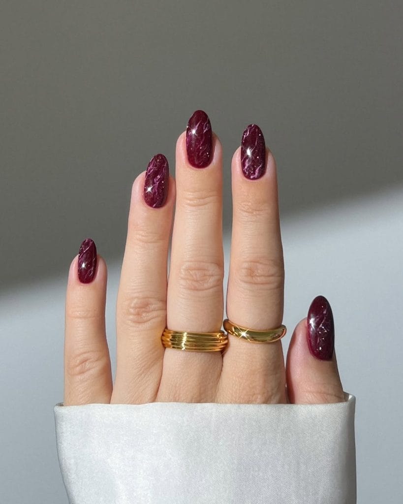 Long oval fall nails with burgundy marble effect polish
