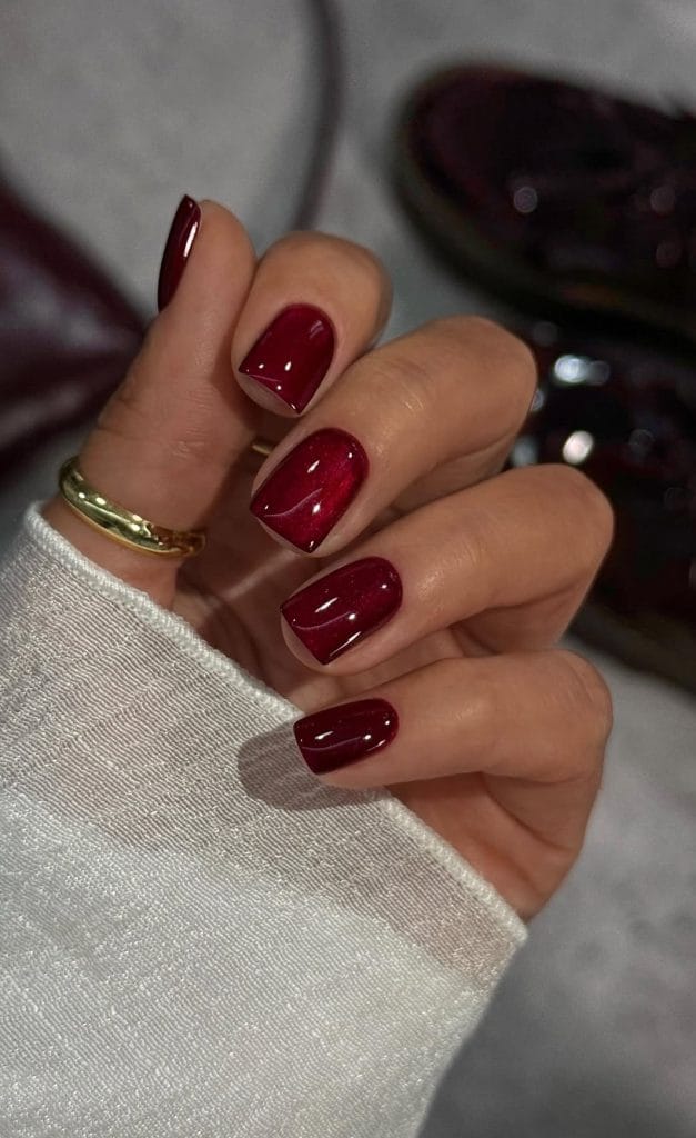 Short fall nails with glossy cranberry red cat eye polish
