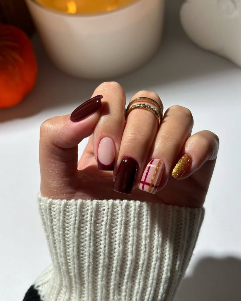 Long fall nails with burgundy, pink with burgundy French tips, gold glitter, and burgundy plaid accent design
