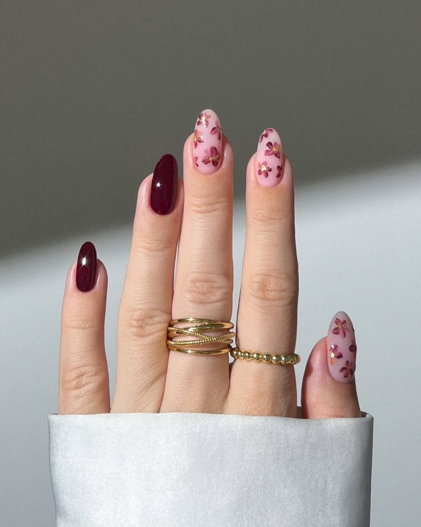 Long almond fall nails with burgundy polish and soft pink floral accent nails with burgundy flower designs
