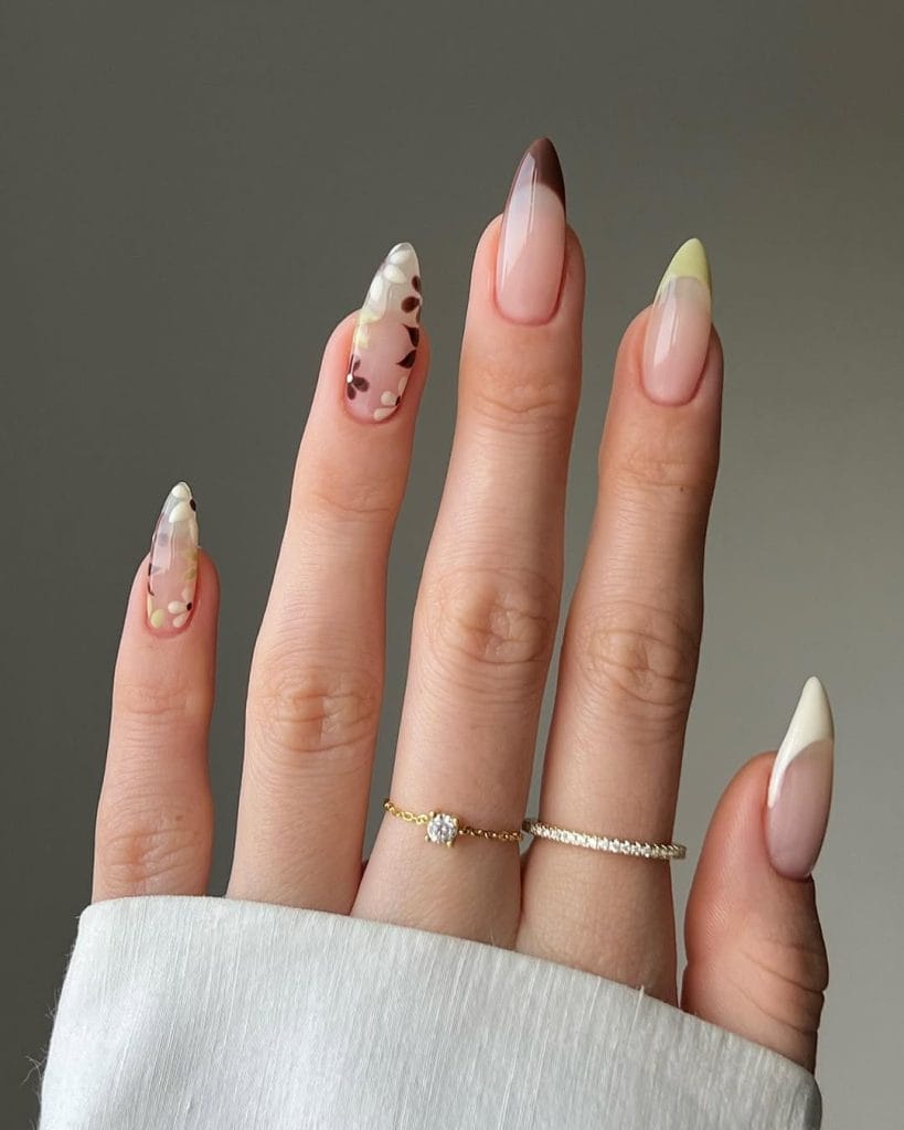 September nails with mixed colored French tips and floral designs on sheer pink base