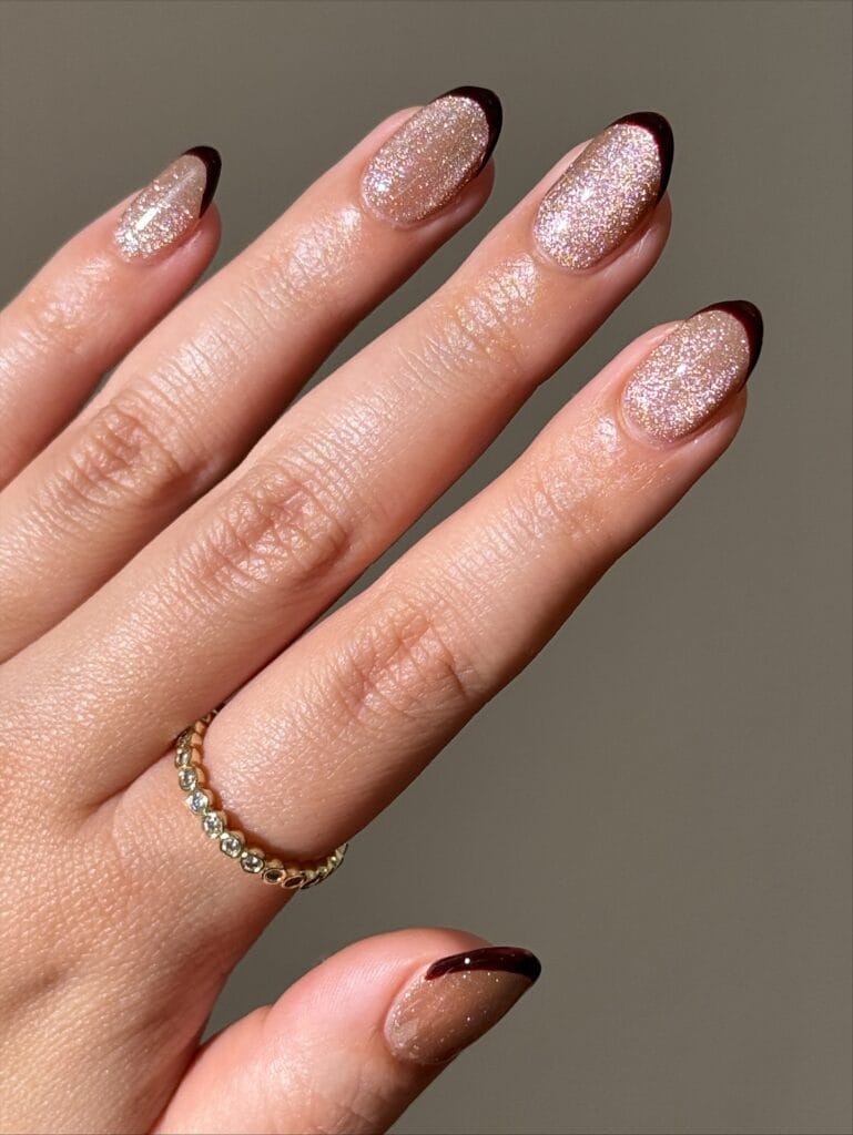 Champagne glitter oval nails with thin dark brown French tips, a simple fall nail idea.