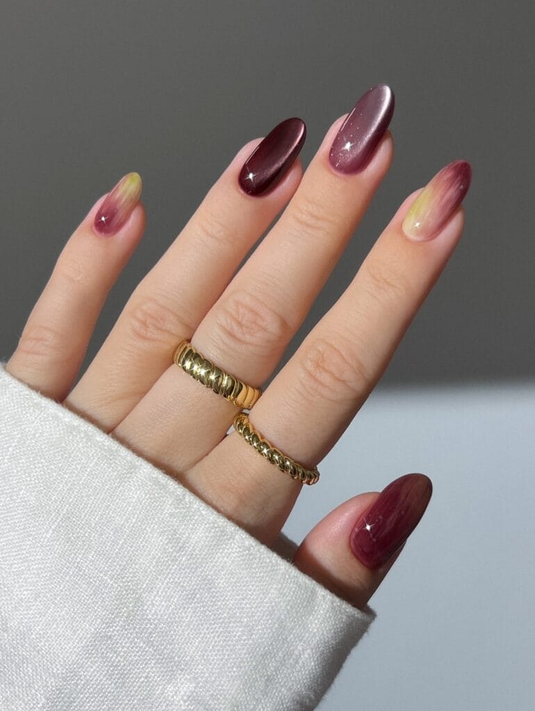 Classy fall nails in wine and mauve shimmer with wispy yellow and berry swirls on almond shapes.
