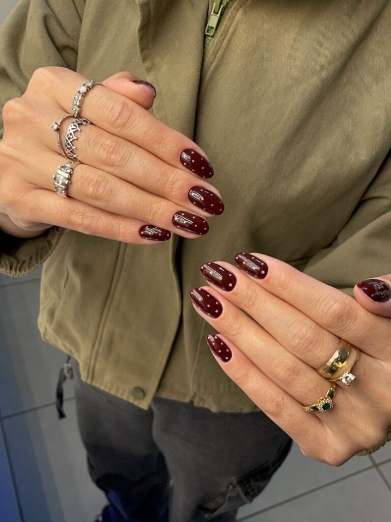Glossy burgundy oval nails with tiny pale pink polka dots for an understated fall manicure.