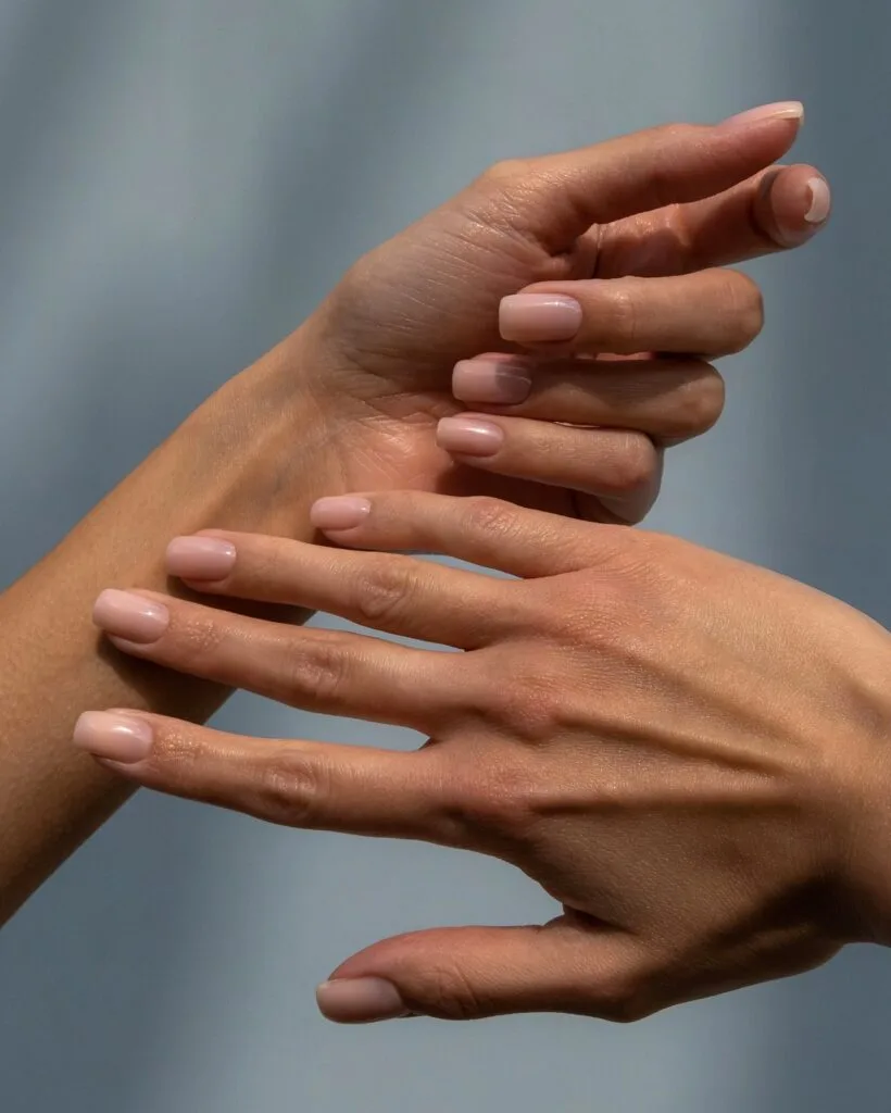 Short, softly squared elegant nails with translucent rosy nude polish.