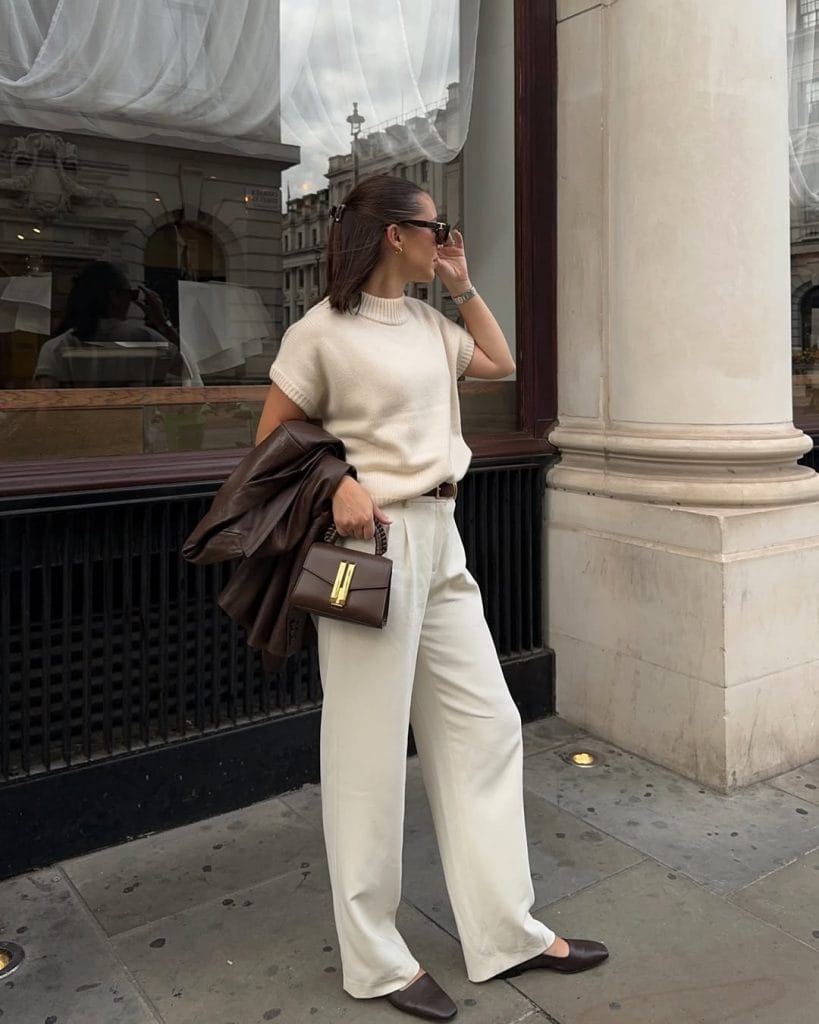 fall work outfit with cream knit sweater, matching wide-leg trousers, brown leather jacket and handbag for office style