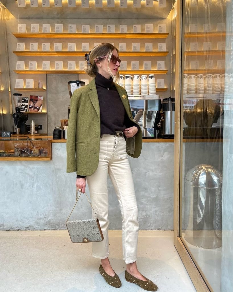 Parisian fall outfit with olive green blazer, black turtleneck, cream pants, studded flats