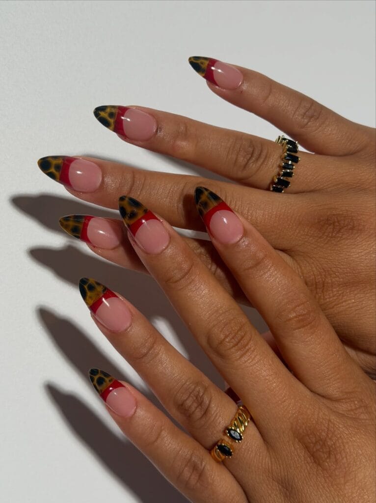 Almond fall French tip nails with nude pink bases, red bands, and amber-and-black tortoiseshell tips