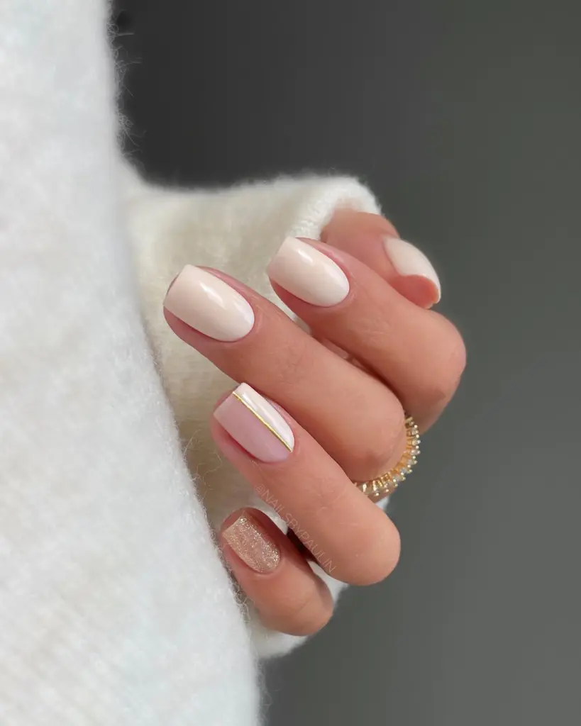 Short fall nails in cream color with half cream half milky design divided by gold line and glitter accent nail