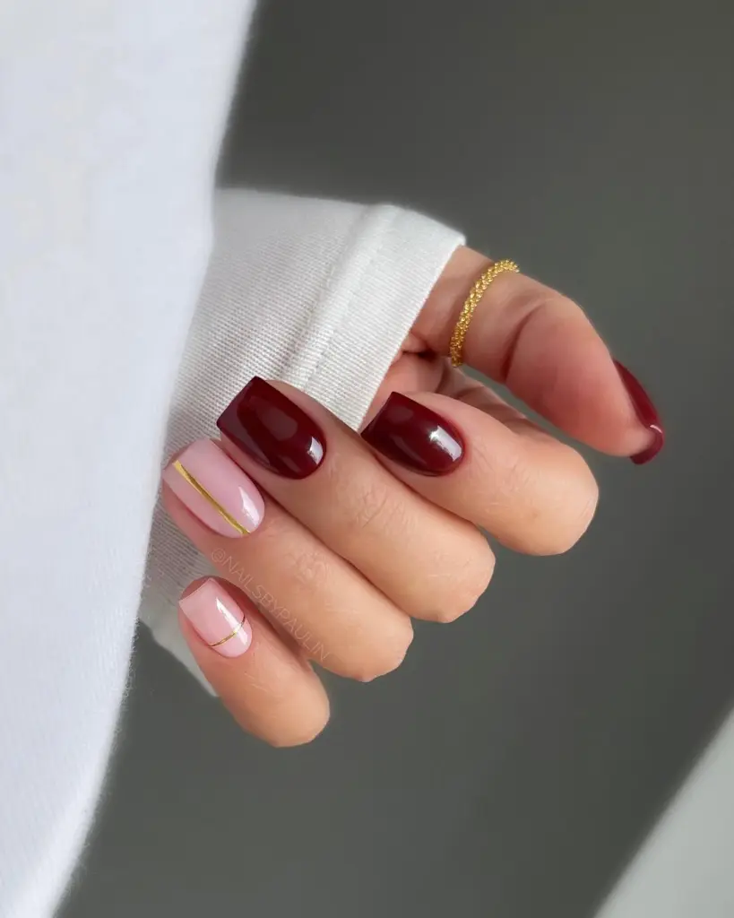 Short fall nails in wine red and milky pink with gold line accent details and glossy finish