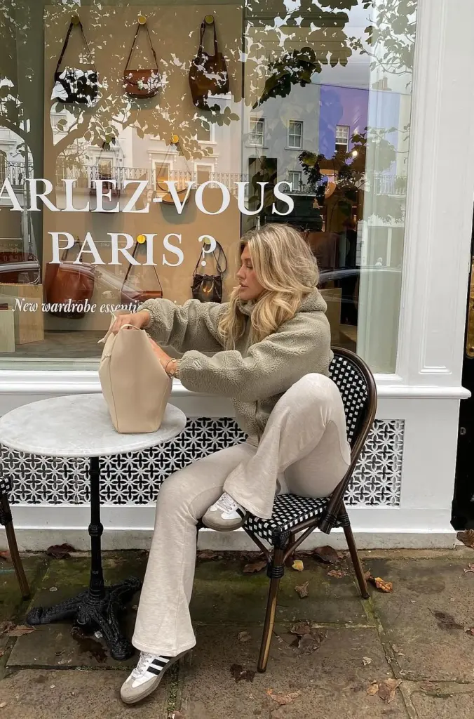 cozy fall outfit with textured sage green hoodie, cream wide-leg leggings, white Adidas sneakers and structured beige handbag