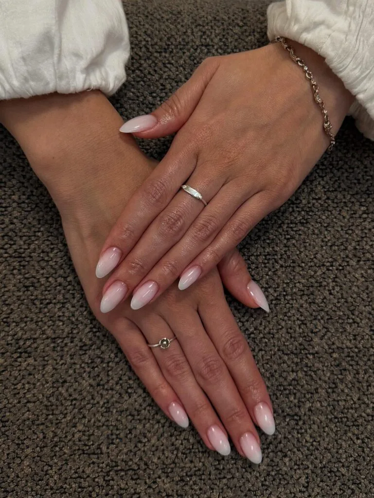 Elegant almond nails with glossy pale pink bases blending into milky white tips.