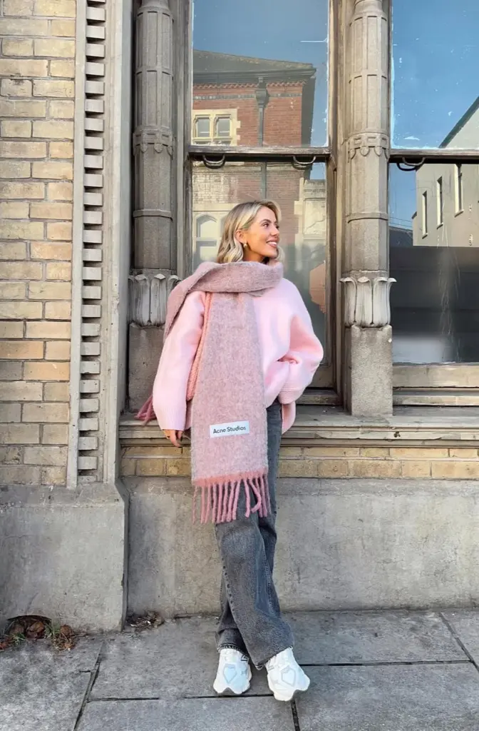 Cozy fall outfit in pink oversized sweater with matching Acne Studios scarf, gray jeans and white chunky sneakers