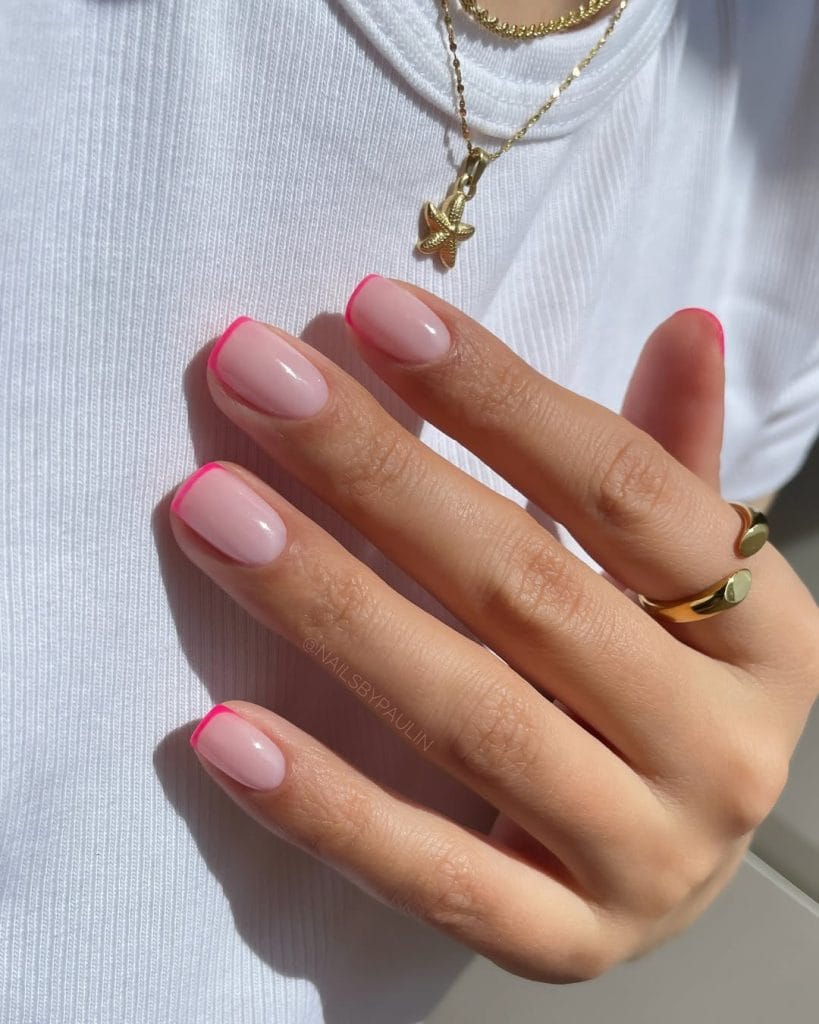 Short summer nails with soft pink base and bright fuchsia French tips