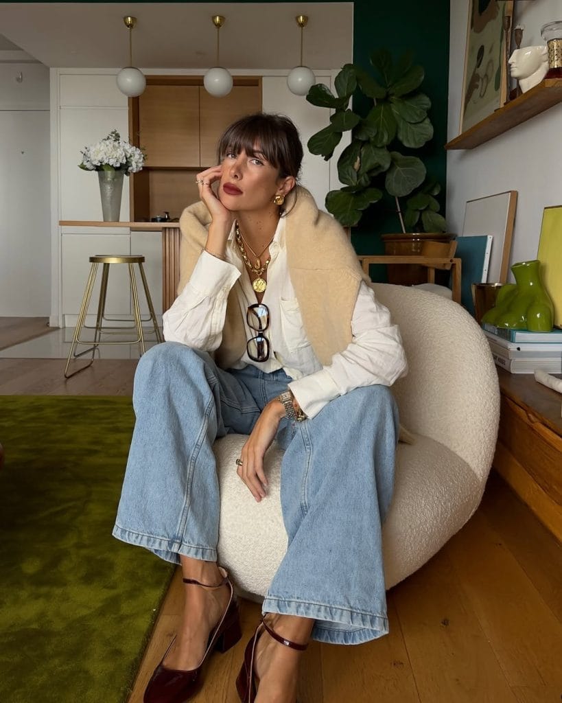 Parisian fall outfit with draped cream sweater, white shirt, frayed wide-leg jeans