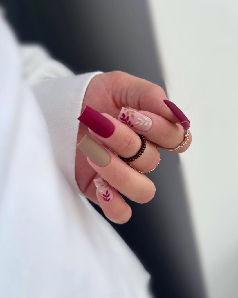 Matte September nails with nude, burgundy polish, and leaf designs