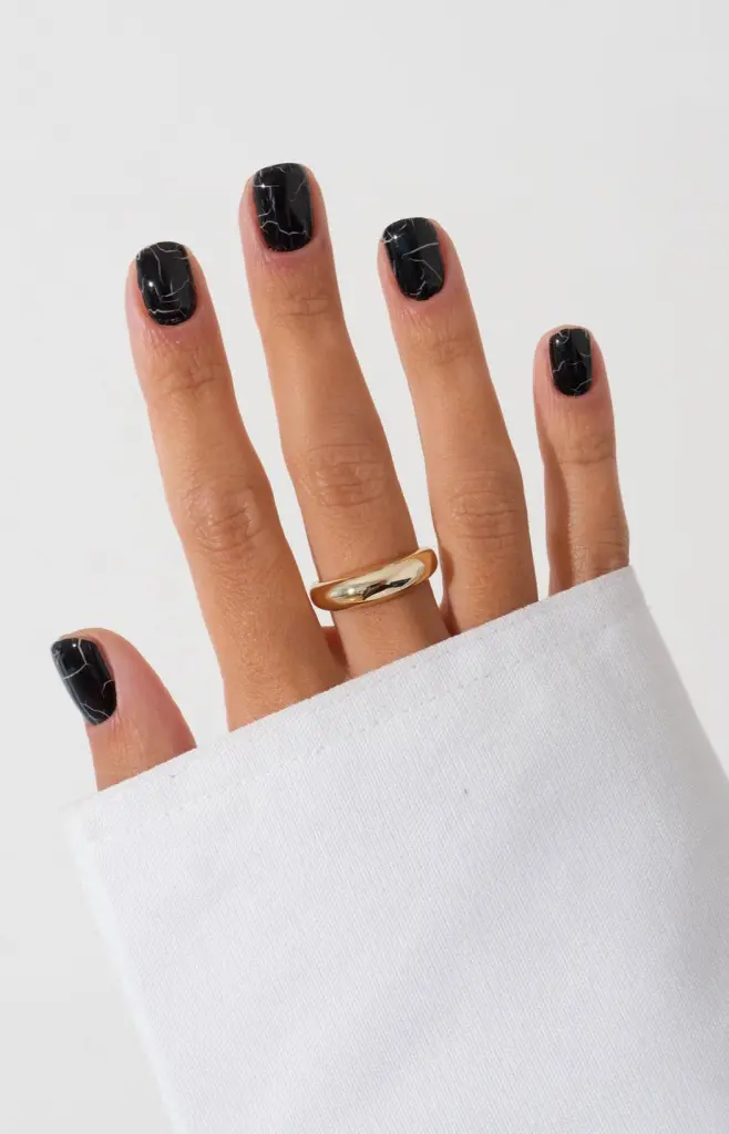 Short fall nails in black with white marble veining pattern and glossy finish