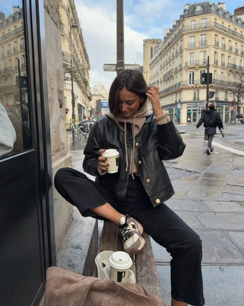 Casual fall outfit with black leather jacket, beige textured hoodie, black pants, beige chunky sneakers
