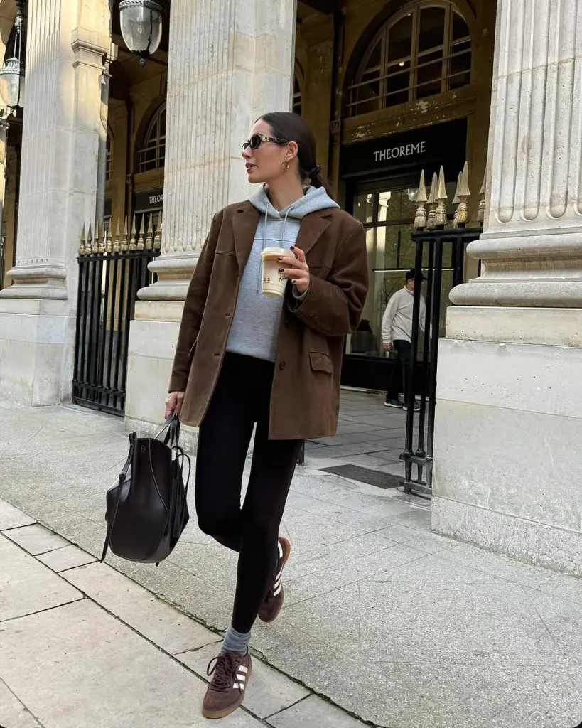 Stylish fall outfit with brown oversized blazer over gray hoodie, black leggings, brown sneakers and black tote bag
