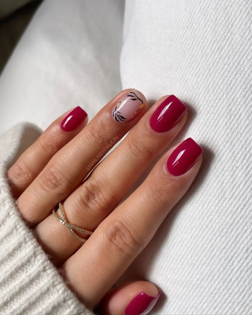 Short berry fall nails with one blush accent, black leaf line art, and small gold foil details.