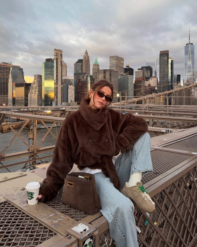 Everyday fall outfit with brown fuzzy jacket, wide-leg jeans, tan sneakers, and brown handbag.

