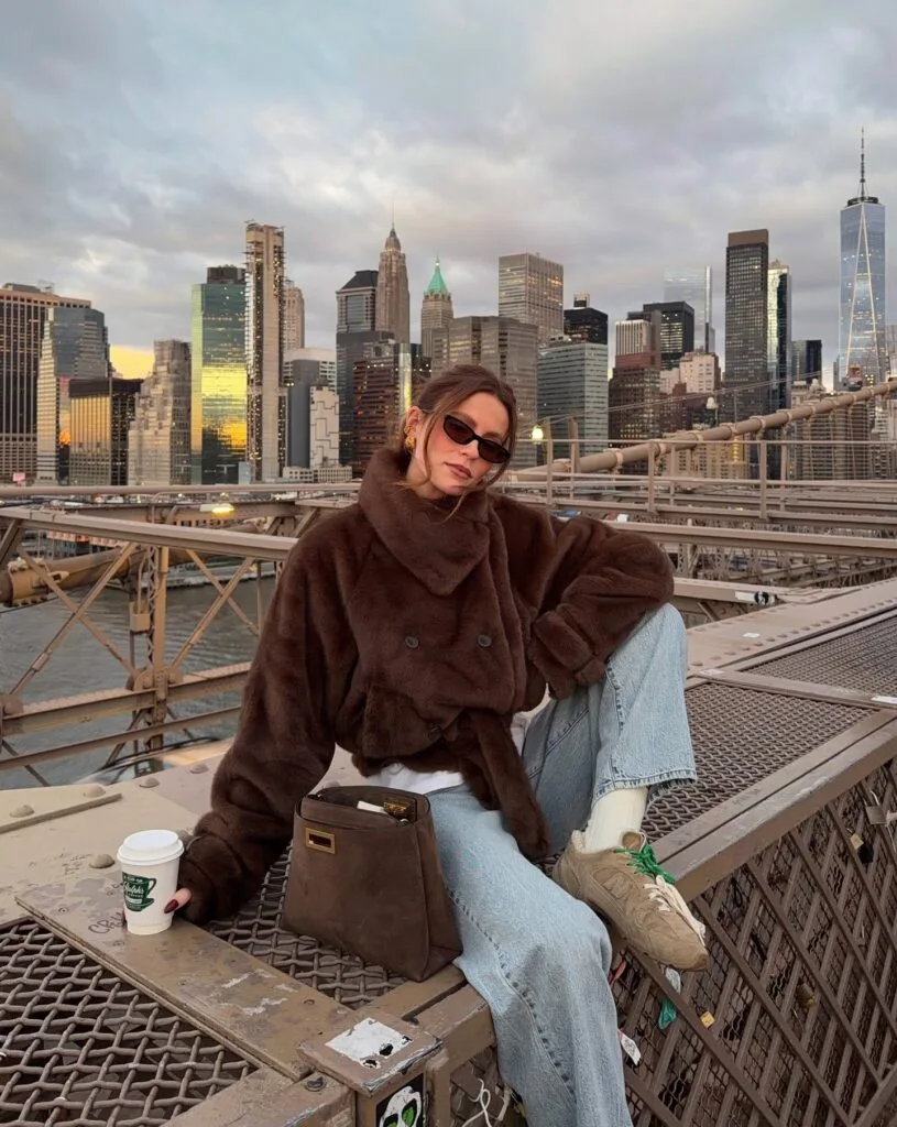 Everyday fall outfit with brown fuzzy jacket, wide-leg jeans, tan sneakers, and brown handbag.
