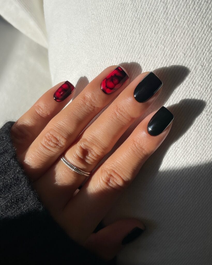 Short square fall nails with glossy black polish and red flowers shaded with black on two accent nails.