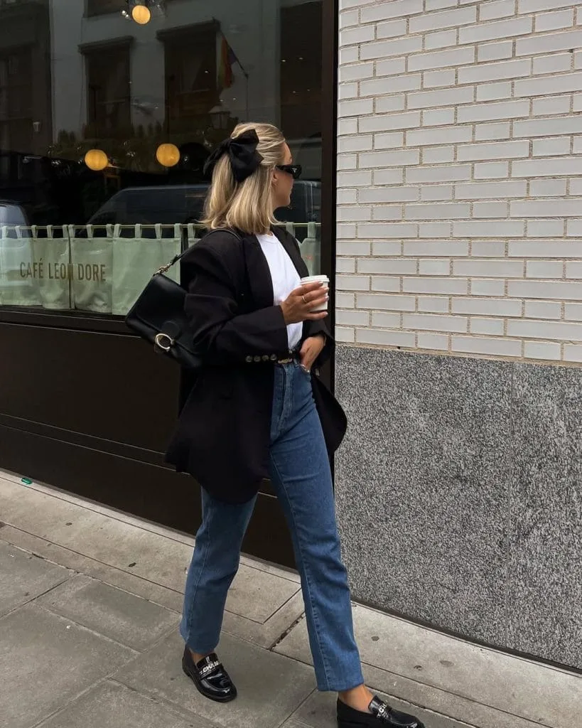 Elegant old money fall outfit with black tailored blazer, white t-shirt, straight leg blue jeans, black chain loafers and silk hair bow