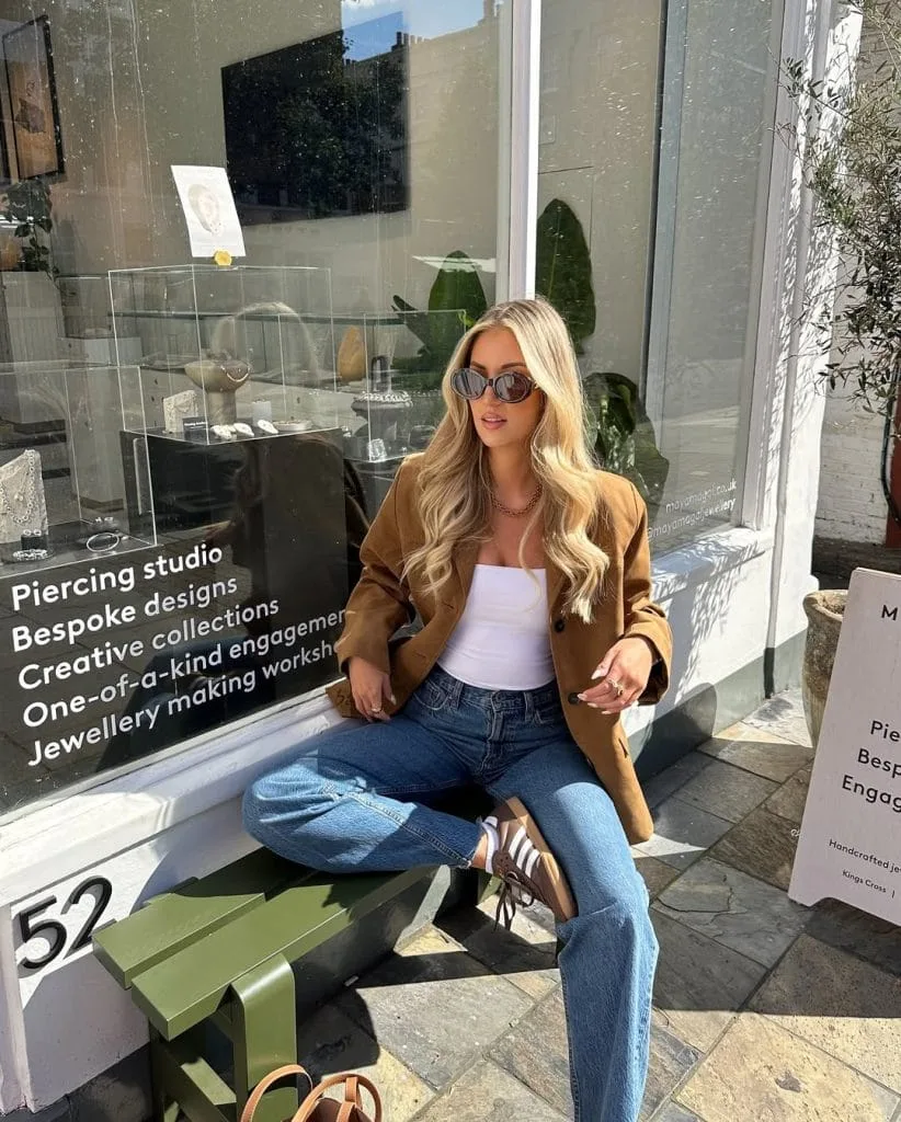 Casual fall outfit with camel blazer, white tube top, medium wash jeans, brown sneakers