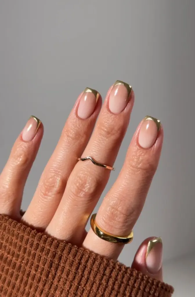 Short fall nails with sheer pink base and gold chrome French tips in glossy finish