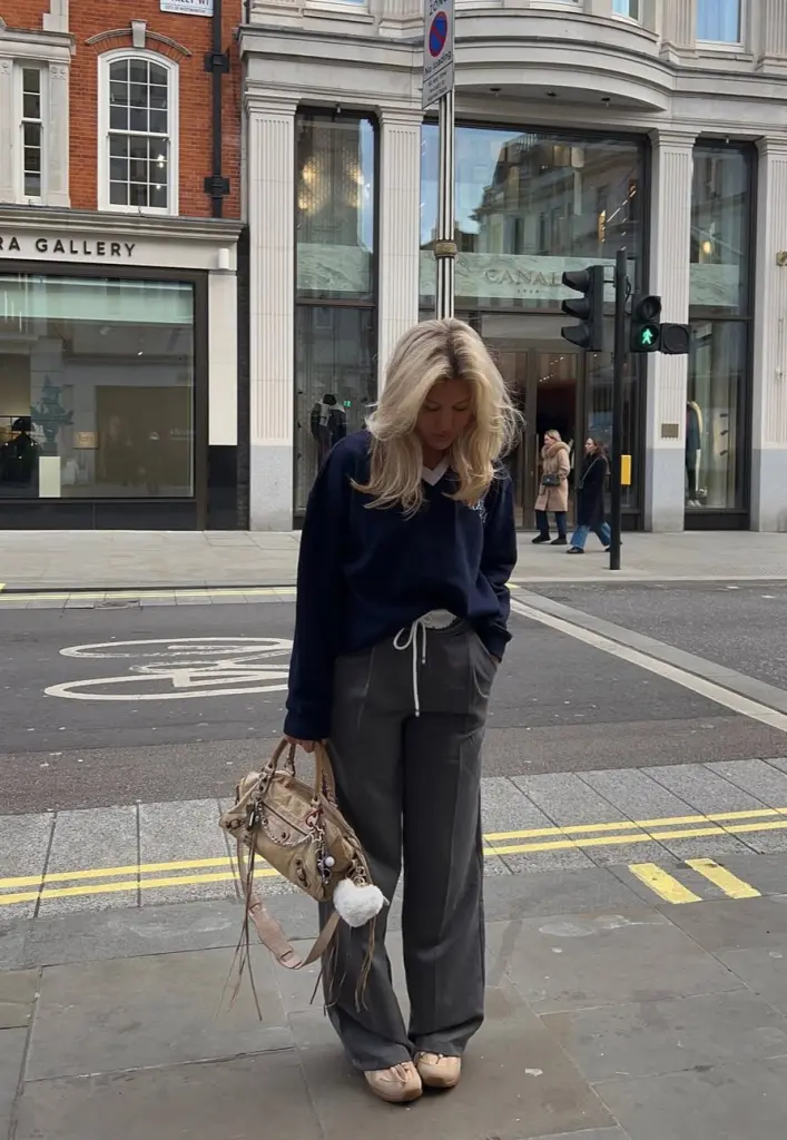 fall outfit with navy oversized sweatshirt, gray double-waist wide-leg trousers, beige sneakers and tan handbag