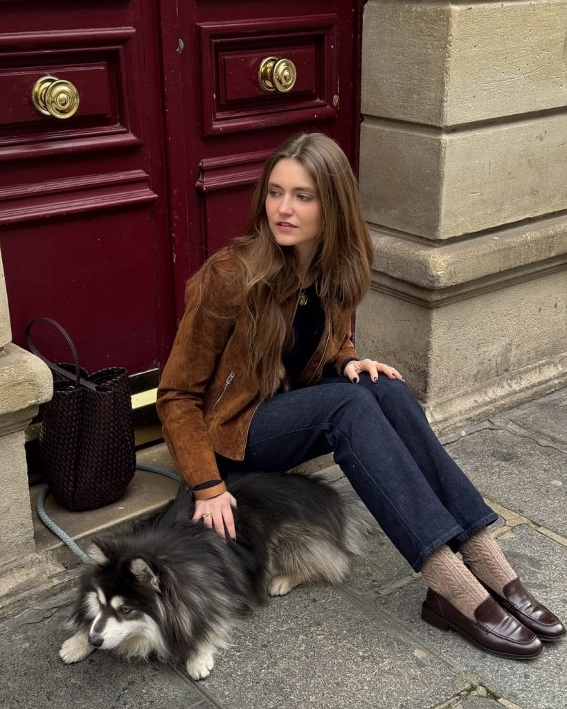 Parisian fall outfit with brown suede jacket, dark jeans, textured socks, brown loafers
