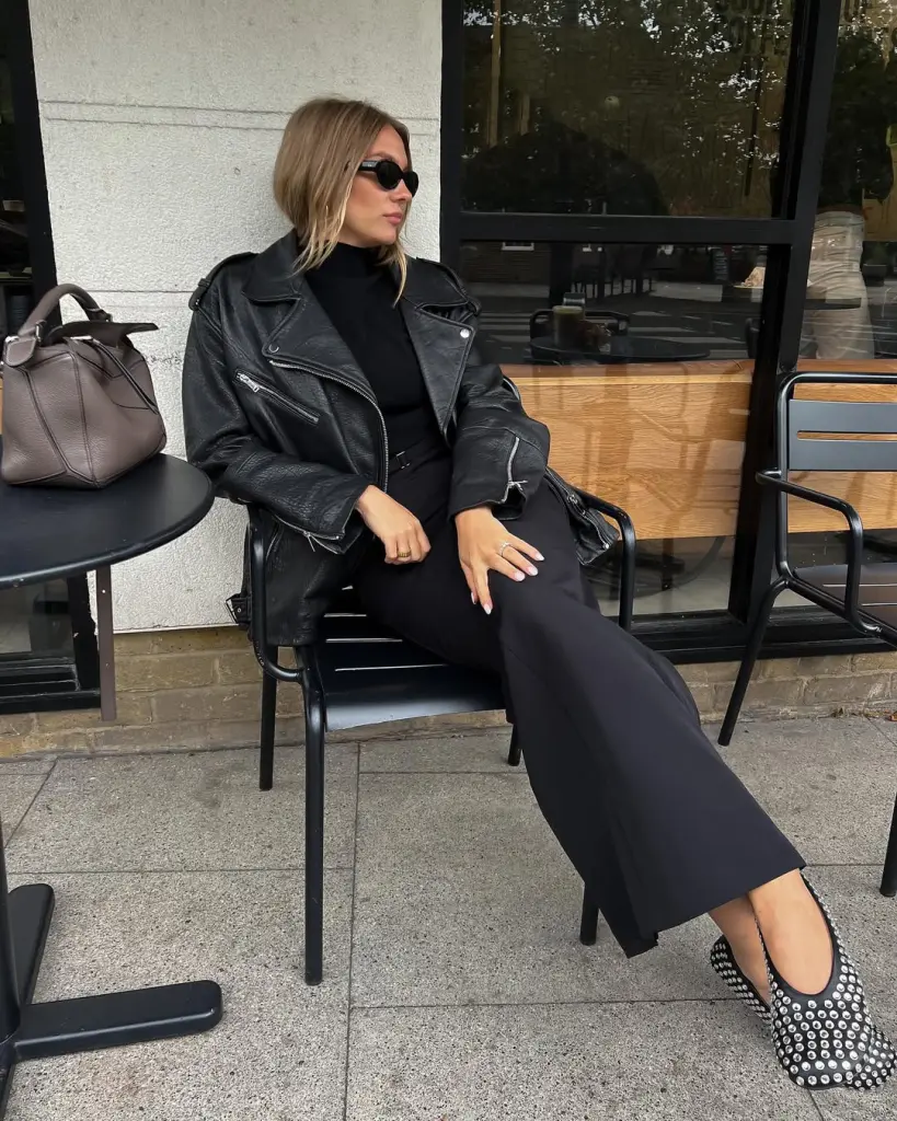 Chic fall outfit with black oversized leather jacket, black turtleneck, black midi skirt, black studded flats and grey handbag
