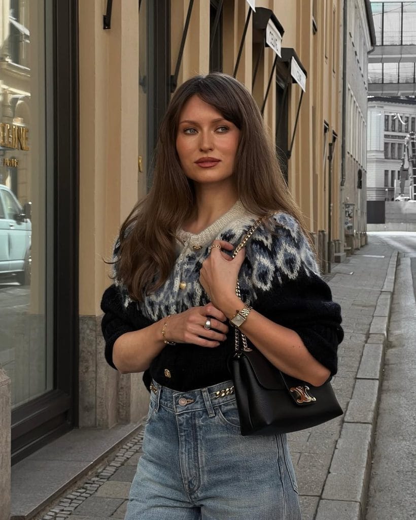 Parisian fall outfit with geometric patterned sweater, wide-leg jeans, quilted chain bag
