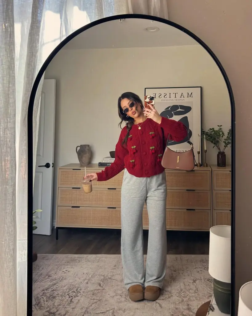 Cozy fall outfit with burgundy cable knit sweater featuring cherry embroidery, gray sweatpants and tan platform Uggs