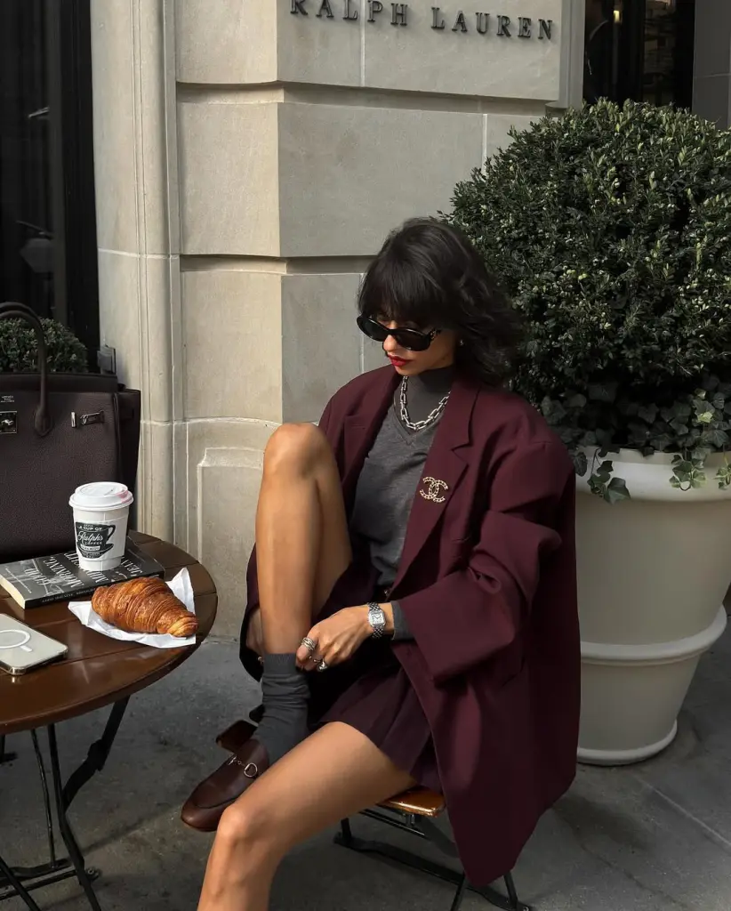 fall outfit with burgundy oversized blazer, grey top, burgundy pleated skirt, and brown horsebit loafers