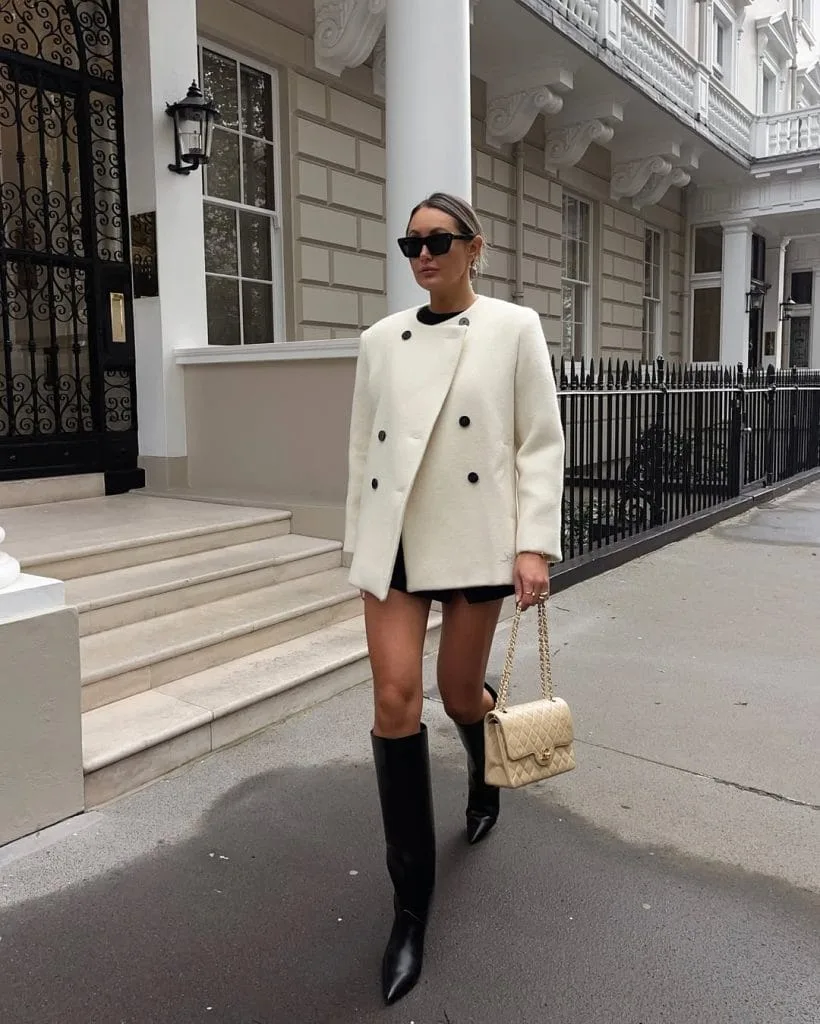 Chic old money outfit with white oversized coat and black knee-high boots